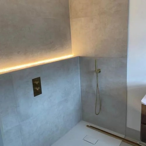Walk-in shower with brushed brass rainfall head and LED strip lighting