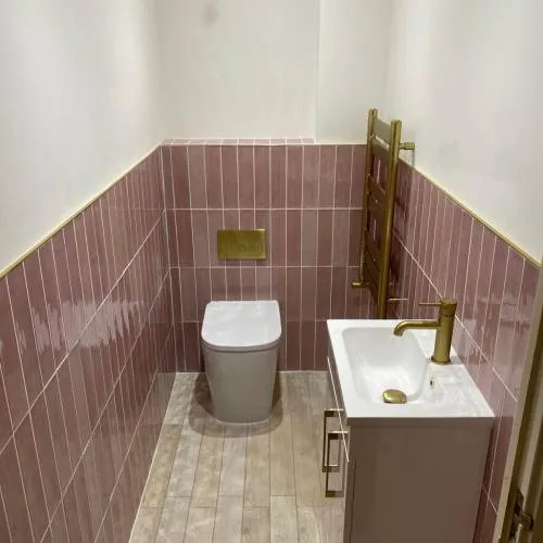 Cloakroom with pink metro tiles, brass towel rail and compact vanity