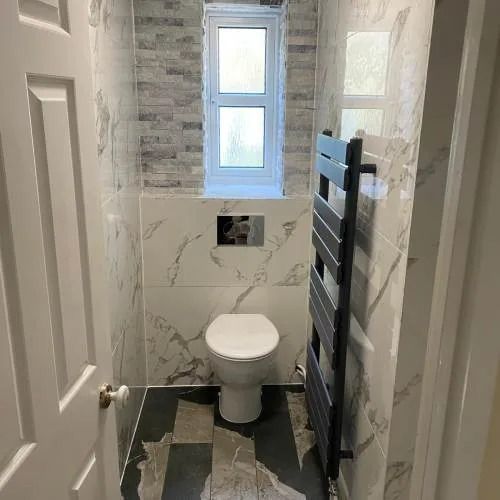 Cloakroom with wall-hung toilet, marble tiles and black towel rail