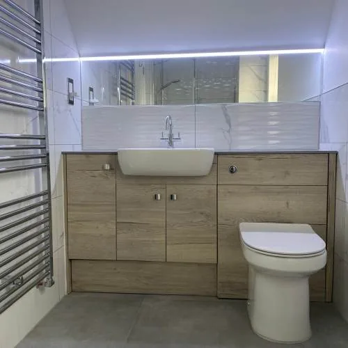 Wood-effect fitted vanity unit with LED lighting and chrome towel rail