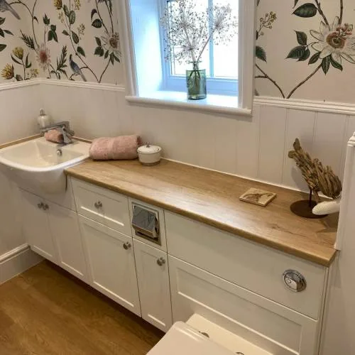 Bathroom with floral wallpaper, wood panelling and an oak worktop