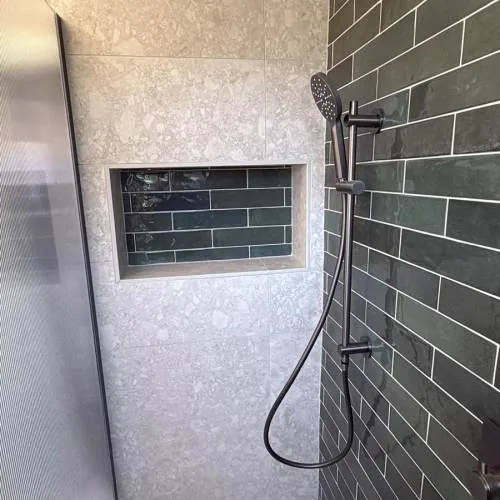 Walk-in shower with dark green metro tiles and a tiled niche