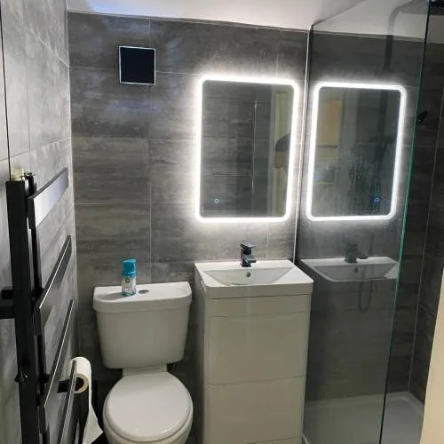 Grey tiled bathroom with twin LED mirrors and a walk-in shower