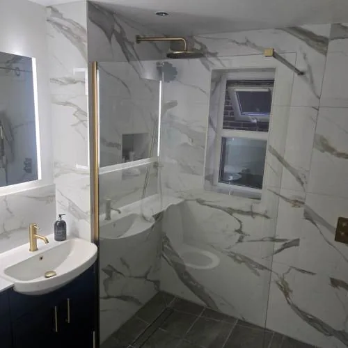 Marble-effect tiled bathroom with brushed brass fittings and navy vanity