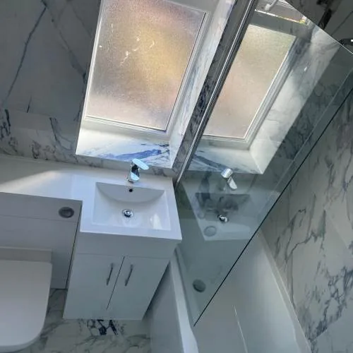 Marble-effect bathroom with bath and white vanity under a skylight