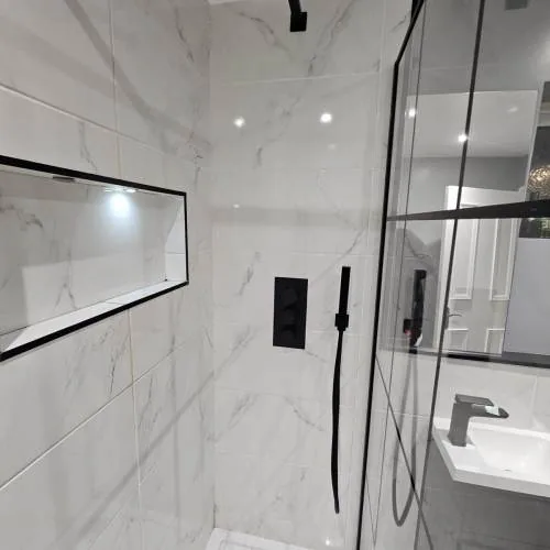 Marble-effect walk-in shower with black rainfall head and recessed niche