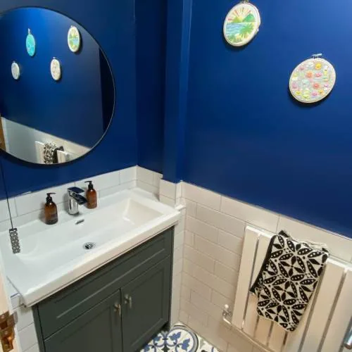 Navy blue bathroom with patterned floor tiles and green vanity unit