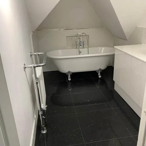 Roll-top bath in a loft bathroom with black sparkle floor tiles
