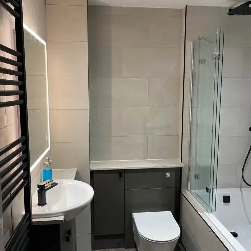 Bathroom with shower bath, black heated towel rail and illuminated mirror
