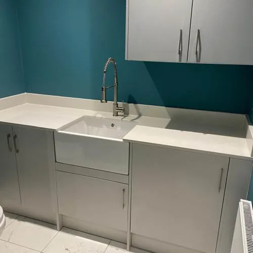 Utility room with Belfast sink, chrome mixer tap and grey cabinets
