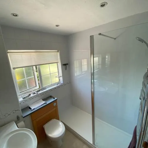 Walk-in shower enclosure with a wood vanity unit beneath the window