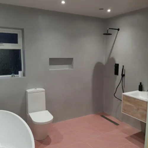 Walk-in wet room with pink floor tiles, grey walls and a black rainfall shower