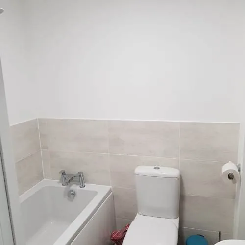 White bath and close-coupled toilet with half-height stone-effect tiling